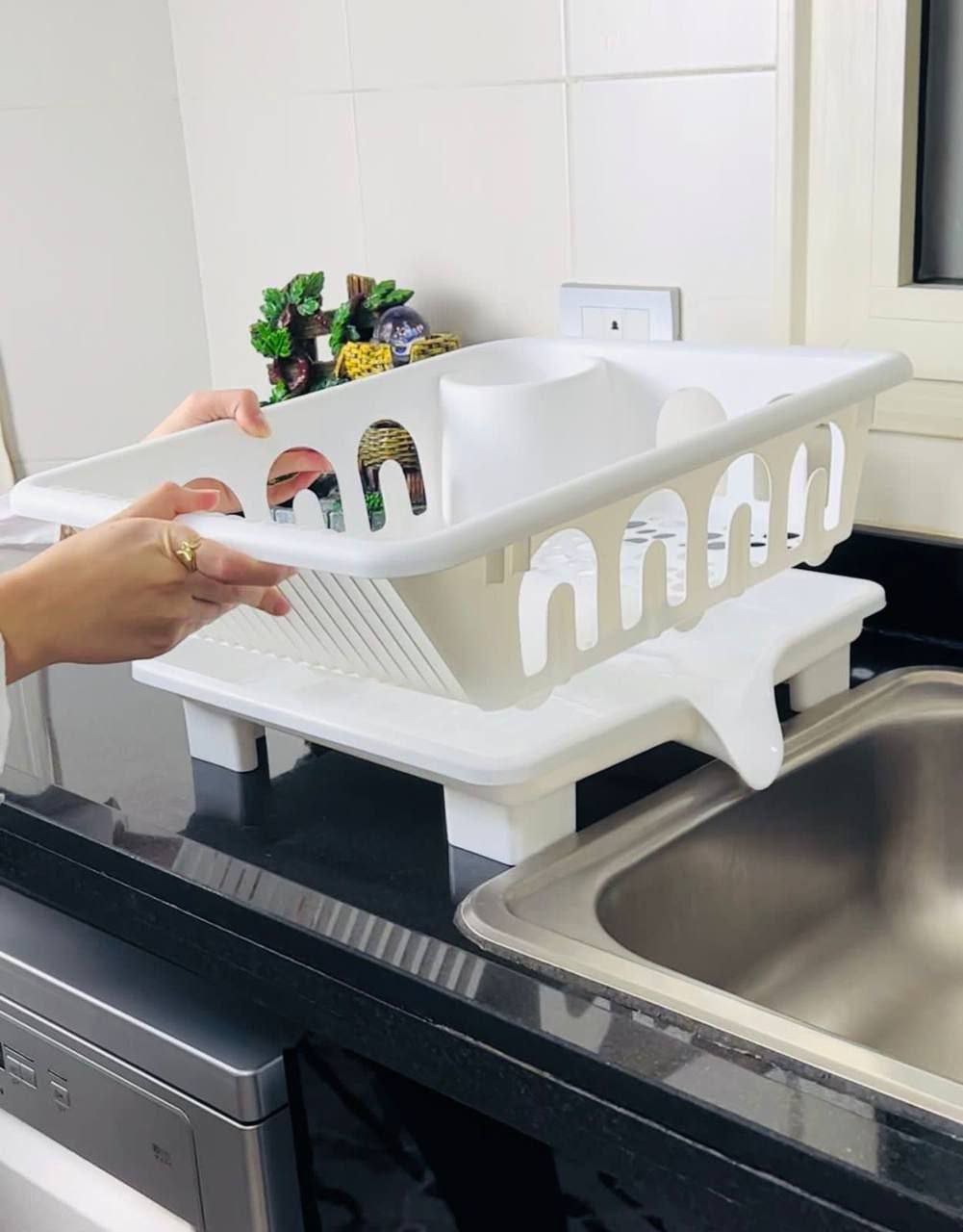 White dish rack being used on a kitchen counter next to a sink.
